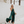 Vrouw in elegante groene maxi-jurk met hoge split, wandelend op trottoir. Zomermode, stijlvolle avondjurk, trendy dameskleding.