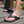 Zwarte unisex teenslippers op houten vloer, comfortabel en stijlvol, ideaal voor zomerse dagen. Perfecte keuze voor casual strand- of buitenactiviteiten.