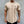 Man in beige T-shirt met halterlogo, toont gespierde armen en tatoeages, draagt gouden armbanden en horloge, tegen grijze achtergrond.