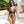 Vrouw in tropisch badpak met bloemenprint en riemdetail, wandelend bij zwembad. Zomermode, strandkleding, stijlvolle zonnebril, vakantie.