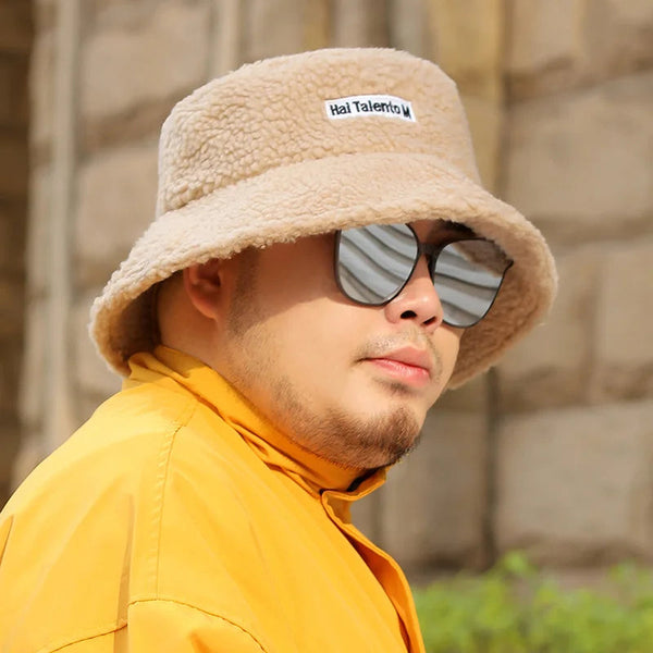 Man met beige teddy bucket hat en reflecterende zonnebril, draagt een gele jas. Stijlvolle wintermode, trendy accessoires, casual outdoor look.