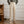 Beige linnen broek voor heren, hoge taille, geplooid ontwerp, casual stijl, gecombineerd met lichtbruine loafers, houten vloer en witte muur.