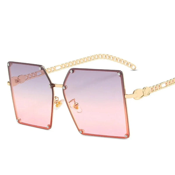 Vierkante zonnebril met roze gradient glazen en gouden kettingpootjes, modieuze damesaccessoire, trendy zonnebrillen 2023.