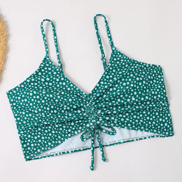 Groene crop top met witte bloemenprint, verstelbare bandjes en ruches detail. Perfect voor zomermode en casual outfits. Trendy dameskleding.