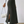 Vrouw in zwarte geribbelde maxi-rok met split, witte sneakers en witte handtas. Modieuze dameskleding, casual stijl, trendy outfit.