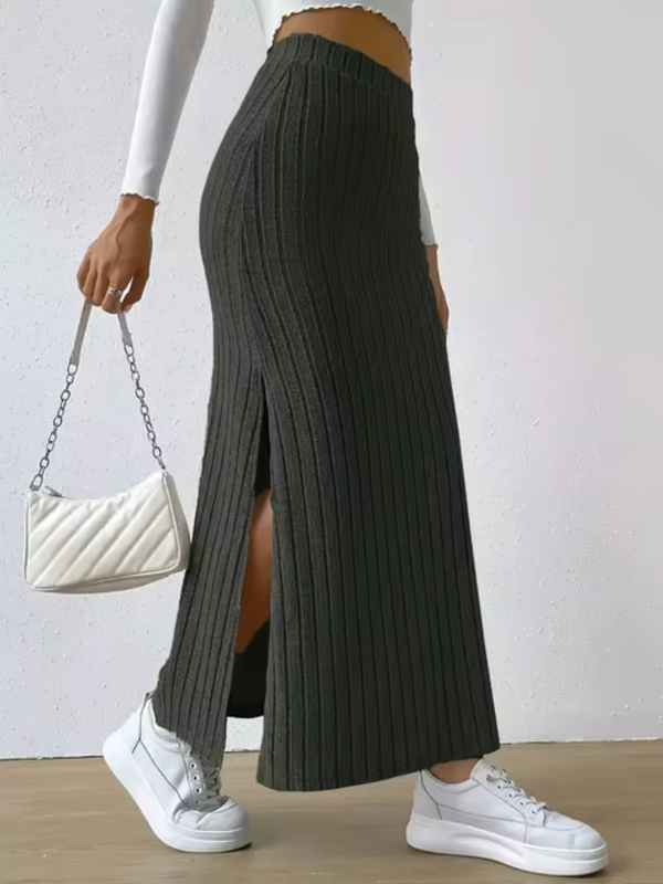 Vrouw in zwarte geribbelde maxi-rok met split, witte sneakers en witte handtas. Modieuze dameskleding, casual stijl, trendy outfit.