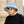 Man met grijze bucket hat en zonnebril, draagt een zwart T-shirt. Stijlvolle modeaccessoires, stedelijke achtergrond, casual look.