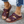 Bruine leren sandalen met open teen en gesp, gedragen door een persoon met blauwe jeans. Comfortabele zomerschoenen voor dames.