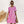Vrouw in roze-wit gestreepte jurk met zonnebril, rieten tas, staand voor witte muur. Zomerjurk, casual mode, dameskleding.