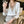 Vrouw in elegante witte blouse met V-hals en beige borduursel, houdt een glas water vast. Stijlvolle kantooroutfit, mode, dameskleding.