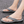 Grijze teenslippers met gevlochten band op asfalt, comfortabele zomerschoenen voor heren, ideaal voor casual strand- en stadswandelingen.