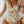 Vrouw in bloemenbadpak met ruches en uitsnijding, liggend op bed. Zomerse strandmode, trendy damesbadkleding, kleurrijk bloemenpatroon.