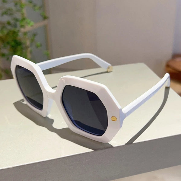 Witte zeshoekige zonnebril met donkere glazen op een grijze tafel, moderne zonnebril, trendy accessoires, stijlvolle damesmode, zomerstijl.