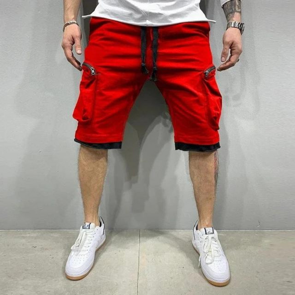 Man in rode cargoshorts met zakken, witte sneakers en wit T-shirt. Casual herenkleding, zomermode, streetwear stijl.