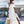 Vrouw in witte off-shoulder jurk met strohoed en rieten tas bij zwembad. Zomerse mode, elegante strandlook, stijlvolle dameskleding.