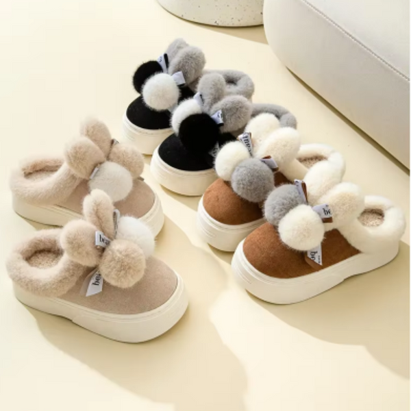 Vijf paar pluche kindersloffen met pompons in beige, zwart en grijs op een lichte achtergrond. Comfortabele winterpantoffels voor kinderen.