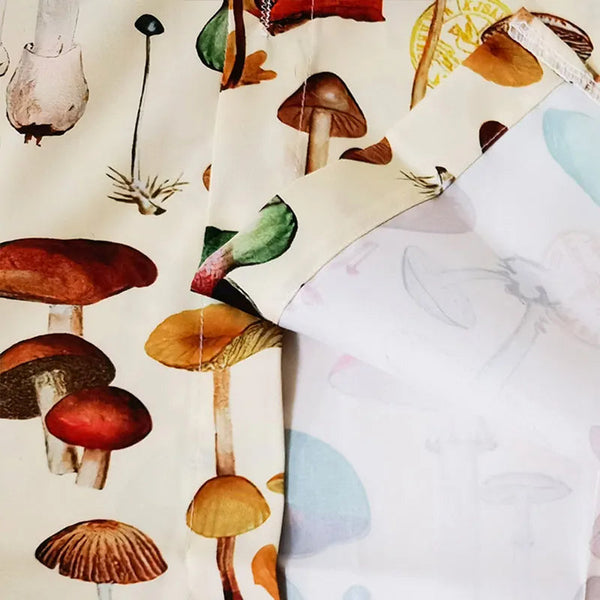 Afbeelding van kleurrijke paddenstoelenprint op stof, met diverse soorten en vormen. Ideaal voor mode, interieurdecoratie en creatieve projecten.