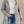 Grijze gewatteerde jas voor dames, stijlvol en warm, perfect voor herfst en winter. Modieuze outfit met spijkerbroek en witte coltrui.