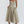 Vrouw in beige midi-jurk met spaghettibandjes en geplooide rok, elegante avondkleding, modetrend 2023, stijlvolle damesmode.