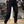 Man in zwarte cargobroek en bruine laarzen, staand in een winkel met motoraccessoires. Casual mode, herenkleding, outdoor stijl.