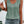 Vrouw in groene mouwloze top met knopen en kanten details, gecombineerd met denim shorts. Zomerse mode, casual outfit, trendy dameskleding.