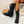 Zwarte leren dameslaarzen met hak, gedragen door model zittend op witte bank. Stijlvolle enkellaarzen, perfect voor herfstmode en casual outfits.