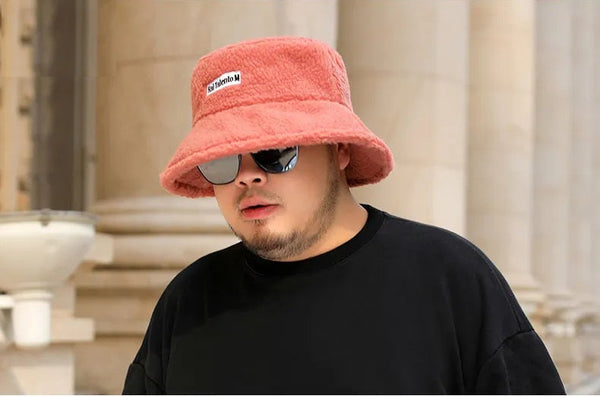 Man met roze bucket hat en zonnebril, draagt een zwart T-shirt. Stijlvolle modeaccessoires, trendy look, stedelijke achtergrond.