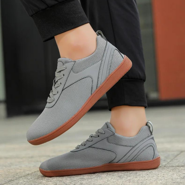 Grijze sportschoenen met bruine zolen, gedragen door een persoon op straat. Comfortabele sneakers voor dagelijks gebruik, ideaal voor wandelen.