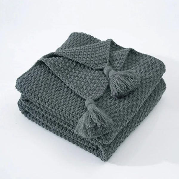 Donkergroene gebreide deken met kwastjes, wafelstructuur, perfect voor woonkamerdecoratie en comfort. Ideaal als stijlvolle plaid of bedsprei.