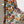Vrouw in kleurrijke bloemenjurk met tropisch patroon, lange mouwen, luchtige stof. Perfect voor zomermode en strandkleding.