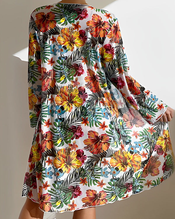 Vrouw in kleurrijke bloemenjurk met tropisch patroon, lange mouwen, luchtige stof. Perfect voor zomermode en strandkleding.