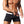 Man in zwarte zwembroek met witte tailleband, gespierd lichaam, glanzende huid, strandmode, zomerstijl, sportieve zwemkleding voor heren.