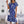 Blauwe zomerjurk met witte bloemenprint, korte mouwen en ceintuur, gedragen door vrouw met witte schoudertas. Perfect voor casual en elegante gelegenheden.