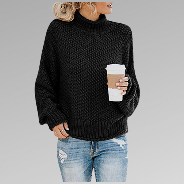 Vrouw in zwarte gebreide trui met col, houdt een kartonnen koffiebeker vast, draagt gescheurde blauwe jeans. Casual herfstmode, comfortabele outfit.