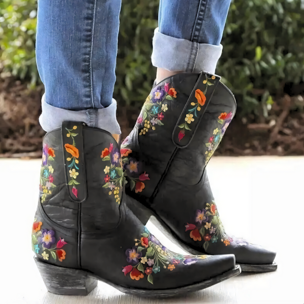 Zwarte cowboylaarzen met kleurrijke bloemenprint, gedragen door persoon met opgerolde jeans. Stijlvolle westernlaarzen, perfect voor modieuze outfits.