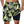 Man in groene zwemshorts met geometrisch palmbladpatroon, hand in zak. Perfect voor strandmode en zomerse activiteiten.