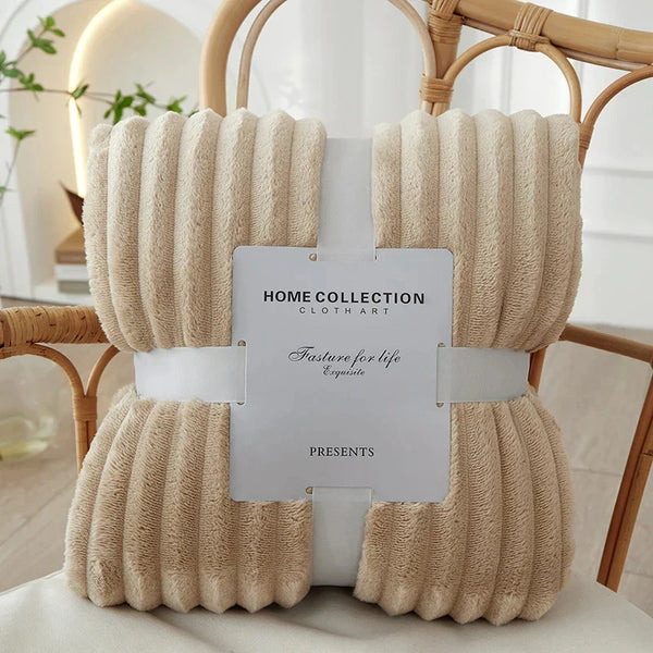 Zachte beige fleece deken van Home Collection, elegant verpakt op een houten stoel. Perfect voor interieurdecoratie en comfort in de woonkamer.