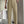 Man in zwarte top en beige pantalon met plooien, houdt witte papieren tas vast. Stijlvolle herenkleding, moderne mode, casual outfit.