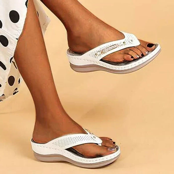 Witte dames sandalen met sleehak, open teen en perforaties, gedragen door model. Comfortabele zomerschoenen, trendy en stijlvol design.