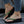 Vrouwelijke voeten in groene, met strass versierde teenslippers met dikke zwarte zolen, gedragen met jeans en een parelarmband. Trendy zomerschoenen.