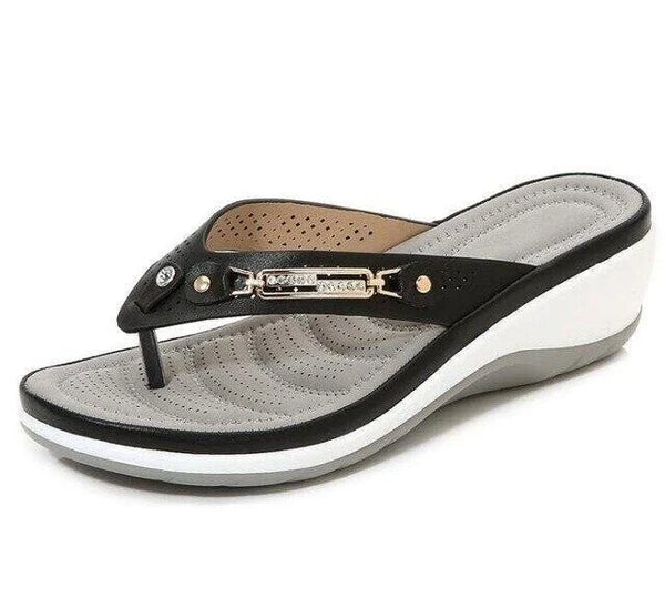 Zwarte dames teenslipper met sleehak, comfortabel voetbed en metalen decoratie. Perfect voor zomerse casual outfits en stranduitjes.