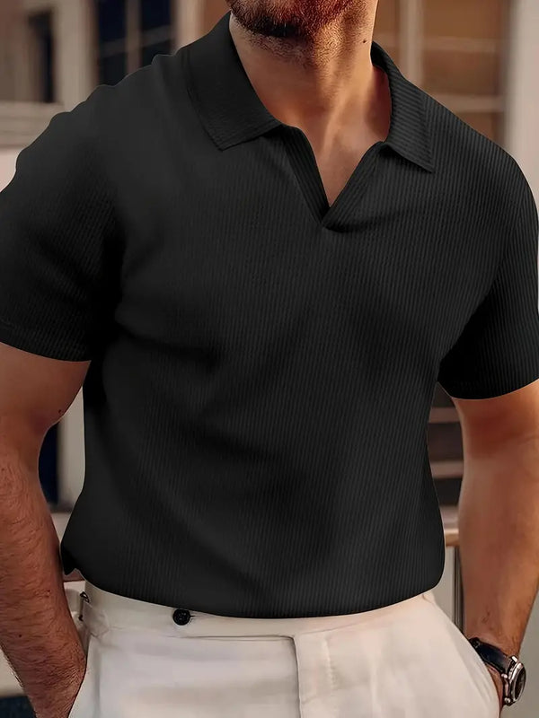 Man in zwarte polo met korte mouwen en ribbeltextuur, gecombineerd met witte broek. Stijlvolle herenkleding, casual en modern design.