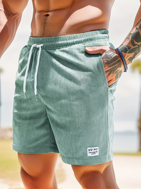 Groene corduroy zwembroek voor heren met witte trekkoord, zakken en merklabel. Perfect voor strandmode en zomerse activiteiten.