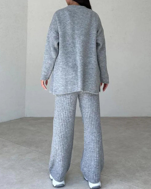 Grijze gebreide dames lounge set, bestaande uit een oversized trui en wijde broek, comfortabel en stijlvol voor casual thuisgebruik.