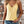 Vrouw in gele kanten top en denim shorts voor bakstenen muur, zomermode, casual outfit, trendy kleding, boho sieraden, stijlvolle look.