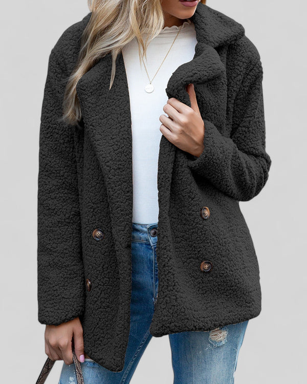 Vrouw draagt zwarte teddyjas, witte trui en blauwe jeans. Stijlvolle wintermode, warme damesjas, casual outfit. Perfect voor koude dagen.