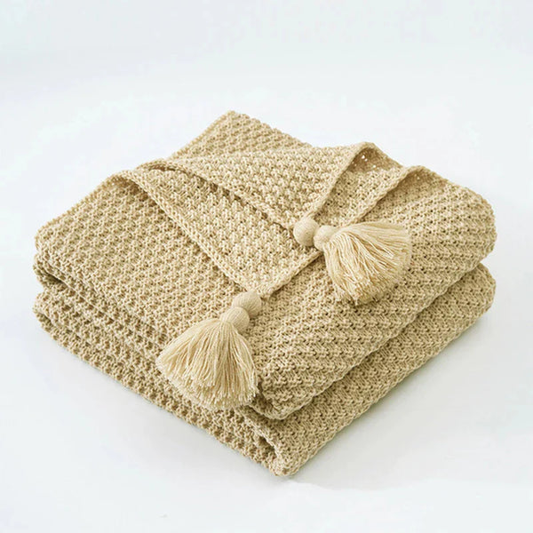 Beige gebreide deken met kwastjes, decoratief en warm, perfect voor woonkamer of slaapkamer. Hoogwaardige katoenen textuur, stijlvol interieuraccessoire.