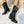 Zwarte leren dameslaarzen met blokhak op witte kiezelstenen, stijlvolle herfst- en wintermode, comfortabele en trendy schoenen.