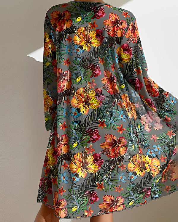 Kleurrijke bloemenjurk met tropisch patroon, lange mouwen en luchtige stof. Perfect voor zomerse dagen en stranduitjes. Modieuze dameskleding.