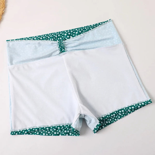 Witte dames zwemshorts met groene bloemenrand, comfortabele pasvorm, ideaal voor strand en zwembad. Zwemkleding, damesmode, zomeroutfit.